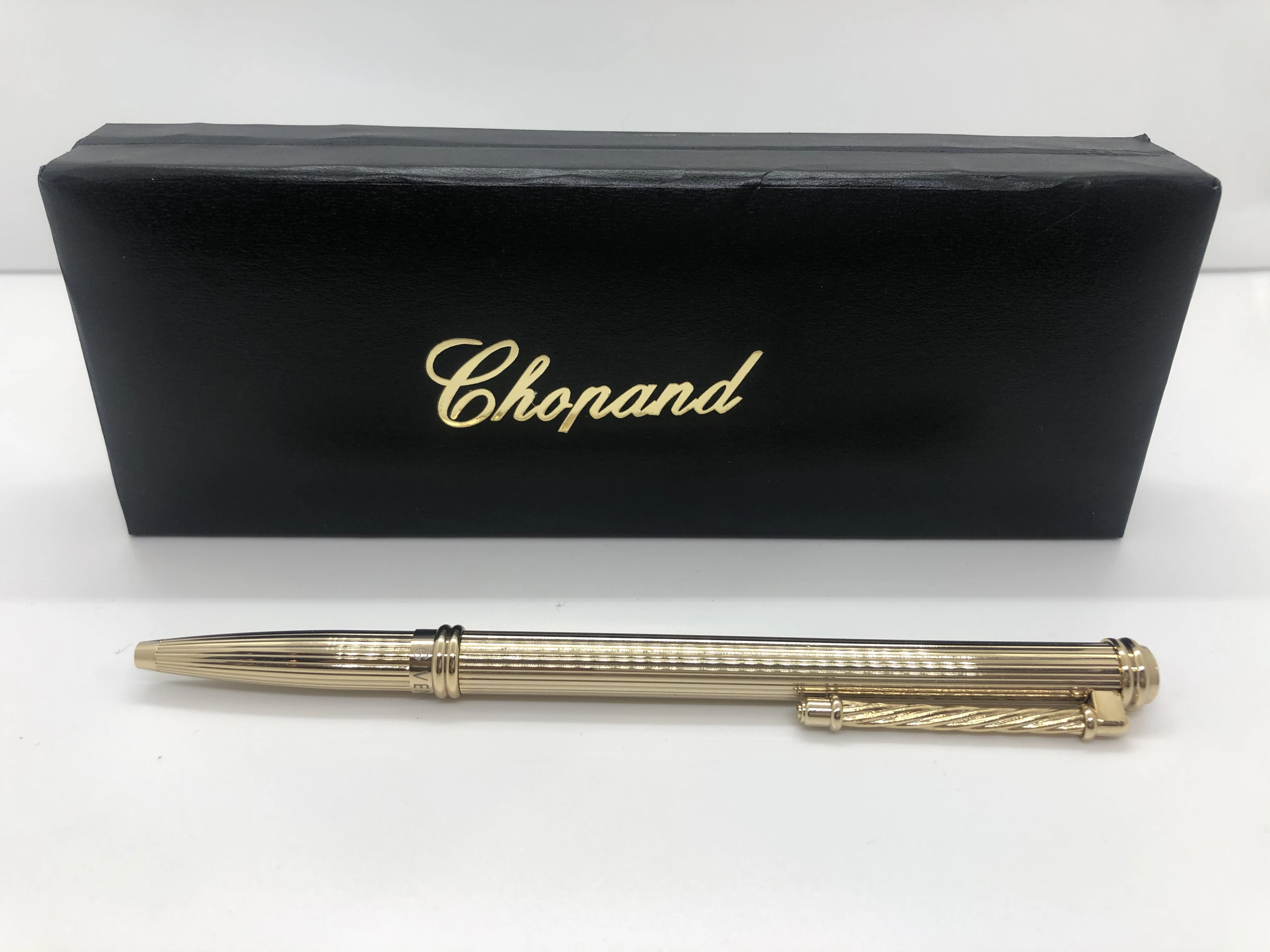 A gold Chopard pen - with embossed touches - with the brand's logo on the top and engraved in the rotation